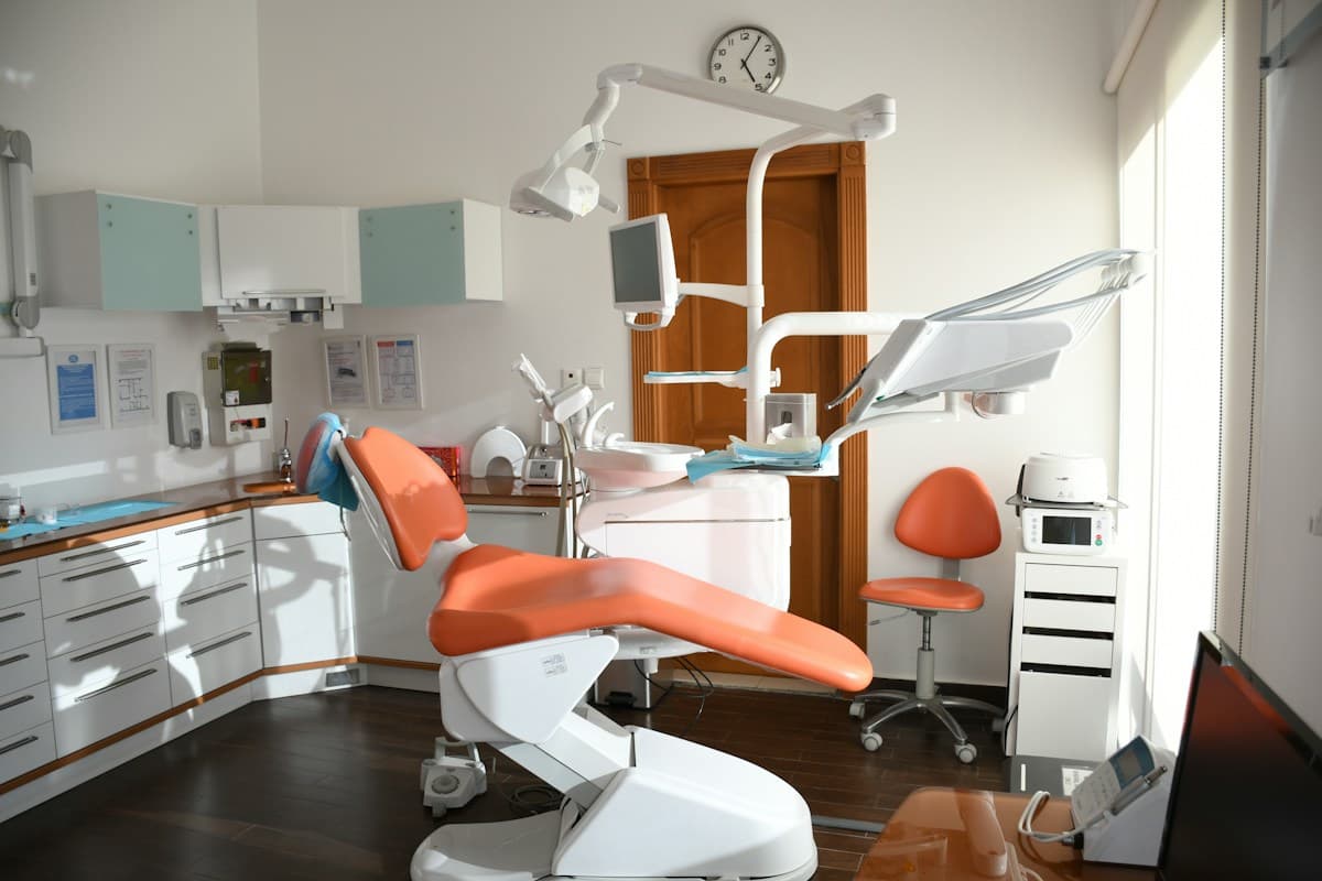 A clean dental chair with modern equipment and an overhead treatment light