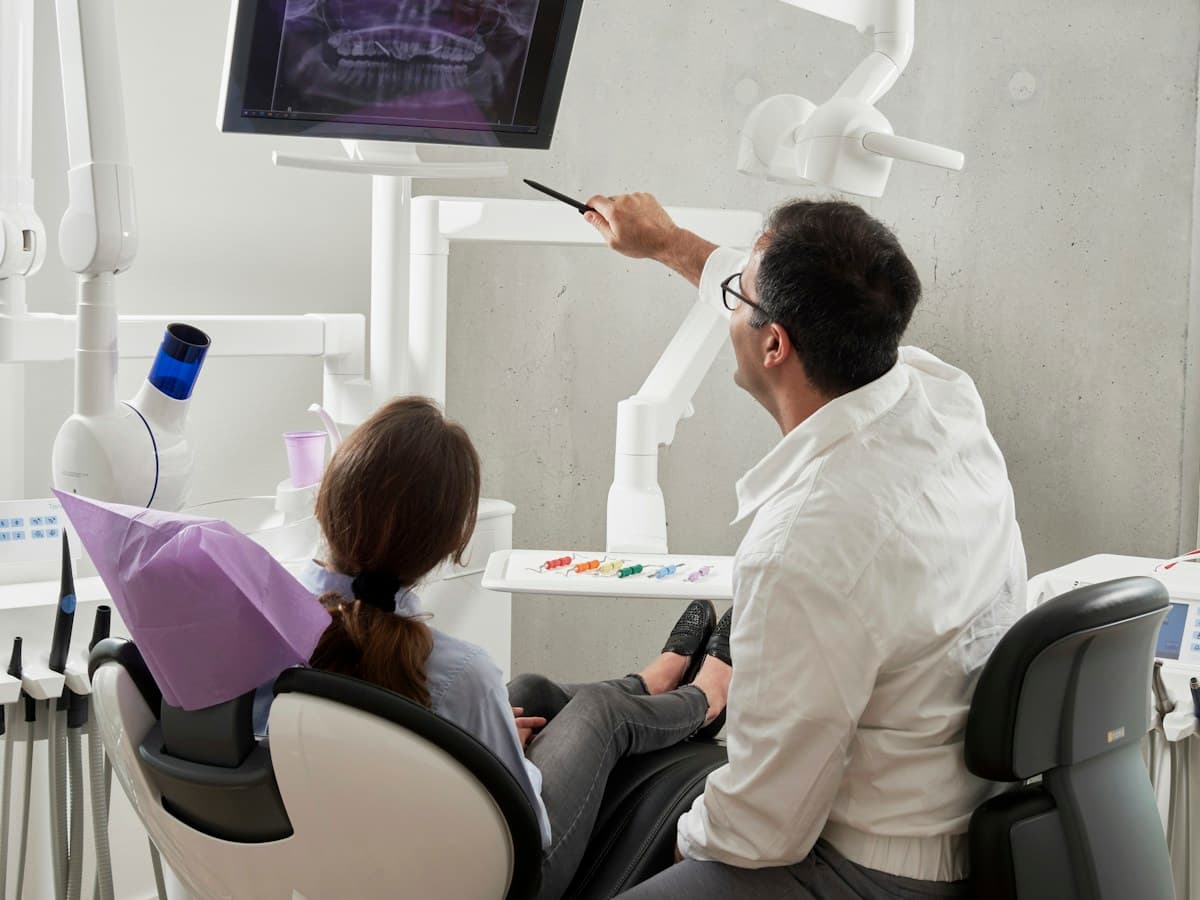 A dentist consulting with a seated patient in a relaxed clinic setting